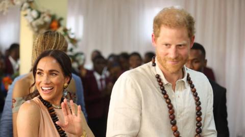 Harry and Meghan wave to people at a mental health summit in a school in Abuja