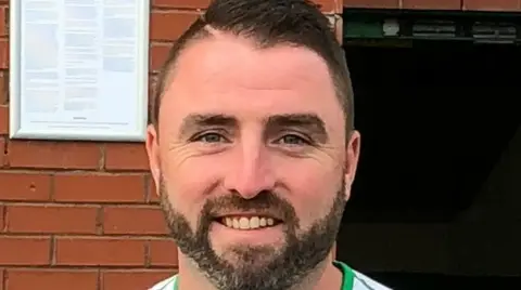 Crossley family A man with brown hair and a beard smiling at the camera.