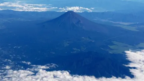 Mount Fuji is pictured from the skies with a ring of white cloud bordering the frame of the image
