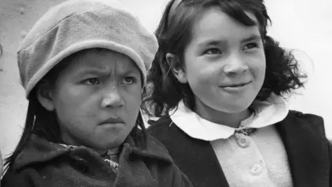 circa 1960: Two little girls displaying opposing emotions
