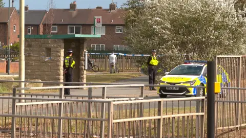 A police cordon at the scene. The road is closed in both directions.