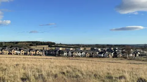A wide shot of the Countesswells housing development outside Aberdeen, showing houses in the middle distance, surrounded by fields.