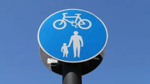 Getty Images a close-up stock image of a blue circular road sign with a white cycling symbol above a white pedestrian symbol.