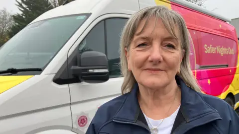 A woman stands in front of a brightly painted band