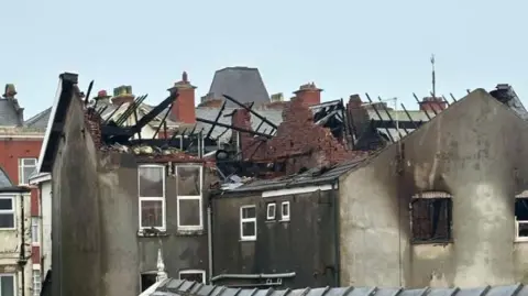 Unspecified The remains of a derelict hotel after it was devastated by a huge fire. The roof is missing, with only charred black rafters remaining.