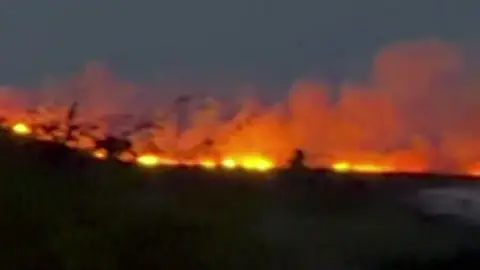  fire with image on the left showing flames on a hill in the dark 