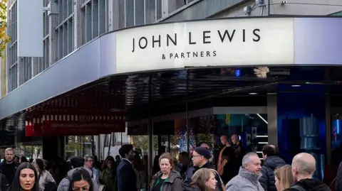 The sign of the Oxford Street John Lewis shop in London with a bustling street below it