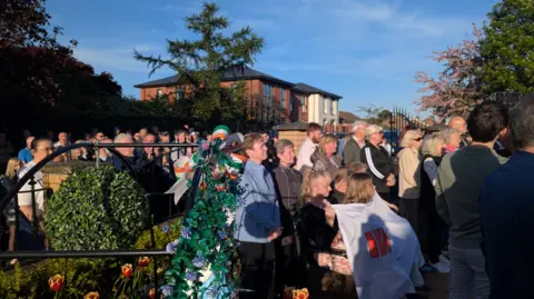 A large group of people standing in a memorial garden.