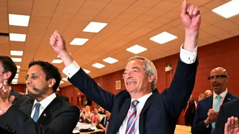 Nigel Farage raises his hands in the air