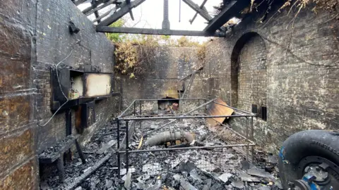 The burnt out interiorof Leighton Pumping Station. There is black rubble on the ground and no roof.