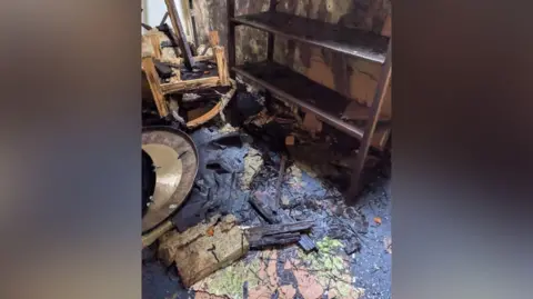 Will Forster MP A view of a dilapidated classroom, with broken furniture and pieces of wood scattered on the ground