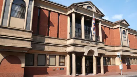 Image of Leicester Magistrates’ Court, which is a red brick building with a Union flag flying outside.