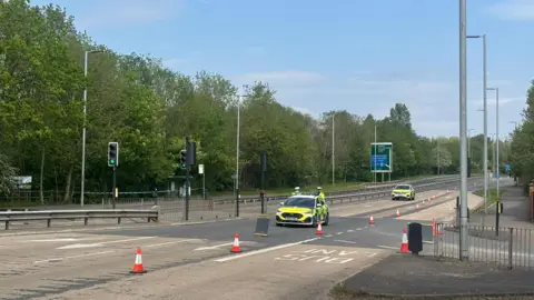 An empty dual carriageway apart from police cars and cones