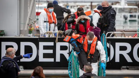 Getty Images A child is carried off  BF Hurricane, a large Border Force boat after being rescued in the English Channel while crossing in a small dinghy. 