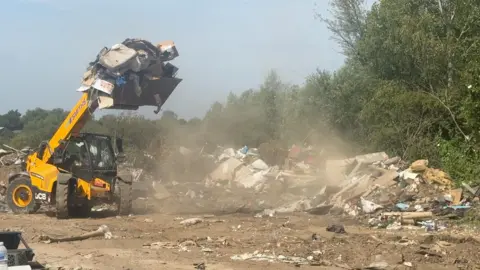 Gloucester City Council A large digger clearing a large pile of rubbish