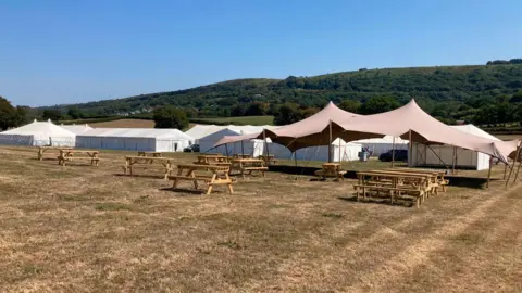 A picture of dry fields with tents and chairs on it.