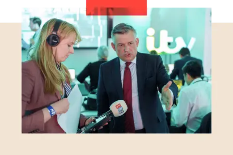 Getty Images Jonathan Ashworth gives an interview to an LBC radio reporter. His left arm is outstretched and he is wearing a suit