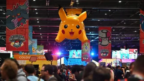 A large inflatable Pikachu floats over a crowd at the ExCeL in London