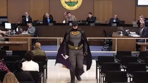 Watch: Man dressed as Batman tells city council to not assist ICE at Super Bowl