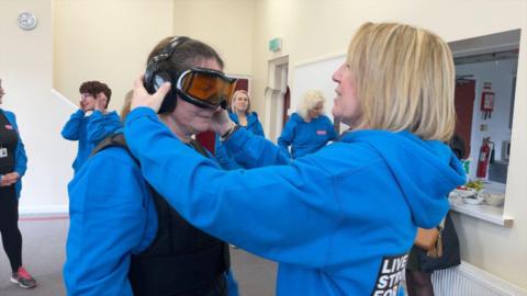 Age UK staff try on age simulation suit 
