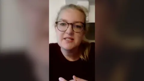 Woman with blond hair and glasses, she is also wearing a black top