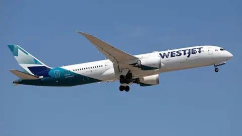A Boeing 747 in flight with the blue Westjet logo on the side and tail colours.