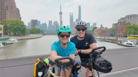 Matt Kidd Jess Gray and Matt Kidd - the couple smile for the camera with their bikes in front of them, while on a bridge.