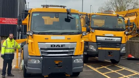 BCP Council Two yellow DAF lorries parked up, facing the camera, with a council worker in hi-vis jacket standing beside