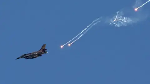 EPA An Israeli fighter jet ejects flares over an area near the Lebanon-Israel border