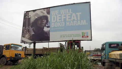 AFP via Getty Images An APC campaign billboard bears the words "we will defeat Boko Haram #EveryNigerianCounts". The words are accompanied by a picture of a soldier, in military fatigues, carrying a gun.