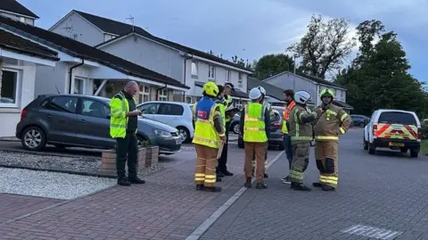 Emergency services gather in a residential street with a taped off cordon in the foreground