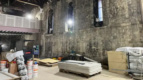 Ongoing building work inside Norwich Castle's keep. There is a pile of plasterboard and building materials cover much of the floor