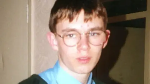 Family Handout A boy wearing round glasses and a blue shirt looking at the camera.