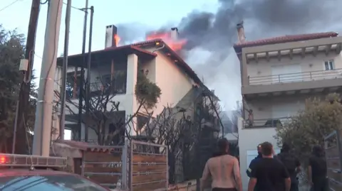 People look up at a burning building