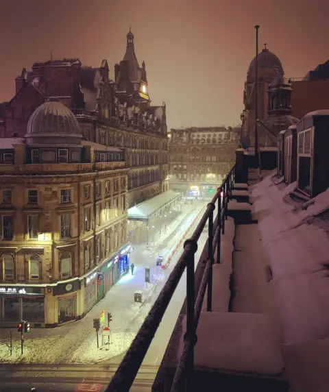 Michelle Cohen Streetlights illuminating the snow on Gordon Street in Glasgow. Central Station is in the background. The dome of the Union corner building is visible in the foreground. 