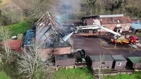 Aerial image of water from a fire engine being sprayed on a building ravaged by fire