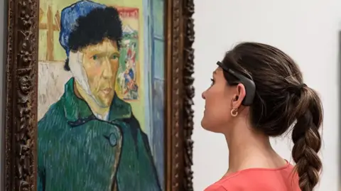 A woman looks at a picture of Vincent Van Gough with a headset on