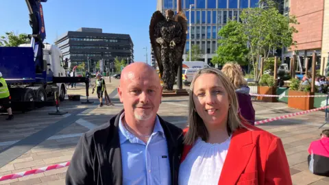 BBC The parents of Connor Brown standing in front of the Knife Angel in Keel Square 