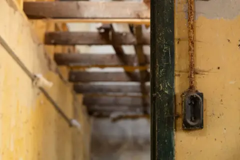 Ray Cartwright An old light switch or power switch against the wall in a disused industrial building