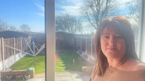 A woman stands at the top of her back garden