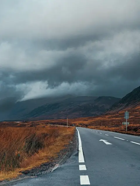 Muhammed Zamaan Empty road in a remote area below a grey stormy sky.
