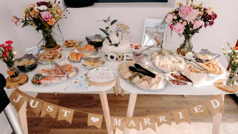 EKR Pictures A table filled with food and flowers with a sign which reads Just Married