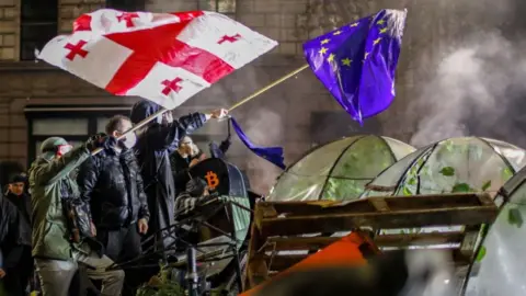 Supporters of Georgia's EPA opposition wave EU and Georgian flags during a protest in front of the Parliament building in Tbilisi, Georgia, early on November 30, 2024.