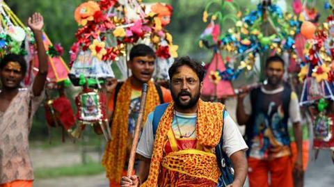 A Kanwariya carries holy water collected from Ganga River in Haridwar during Kanwar Yatra at Sector 14A, on July 10, 2023 in Noida