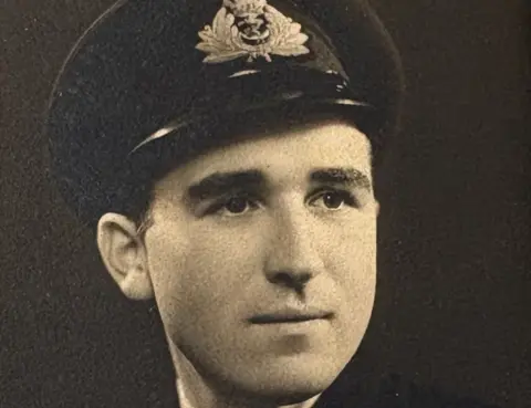 Ruth Pole A black-and-white photo of a young man in military uniform. He is wearing a black jacket and a cap.
