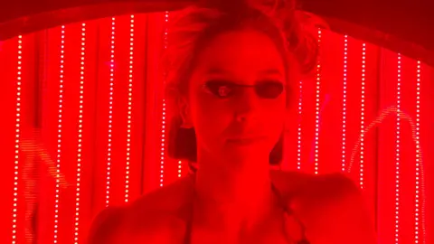 Ruth Clegg BBC Kate McLelland on a red light therapy bed. You can see her face and she is wearing black goggles and a bikini