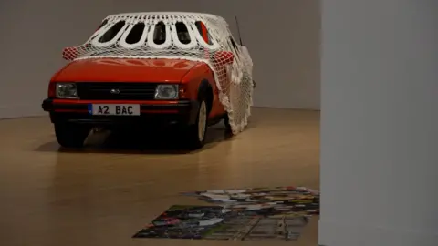 Jasleen Kaur's piece features a vintage orange Ford Escort covered by a white doily. 