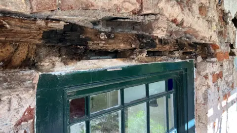 Rotten lintels above a window in a stonewashed 17th centurt building.