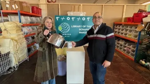 Charnwood Eco Hub Emma Ward holding a giant teapot and pretending to pour into a mug, which is being held by a man