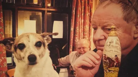 Contributed Lawrence Dixon is sitting on the right behind a bar and is looking at a white and beige dog which is on the left. There are people sitting behind him in front of windows which have red floral curtains.